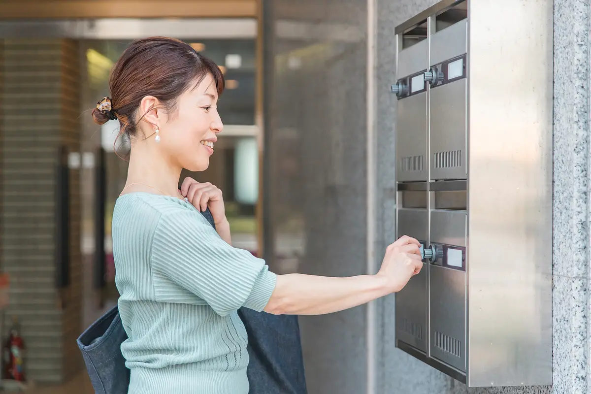 マンションの集合ポストを開ける女性
